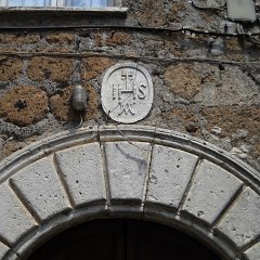 Trigramma bernardiniano sul portale bugnato di una csa del centro storico