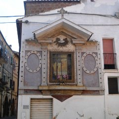 Grande edicola-altare sosvrastata da Croce e Colomba dello Spirito Santo con nicchia affrescata con Madonna e Bambino