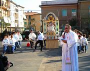 Il parroco Don Andrea invita alla preghiera e ai canti, mentre la Minimacchina viene preparata per il trasporto