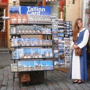 Una ragazza in costume tipico vende guide di Tallinn ai turisti